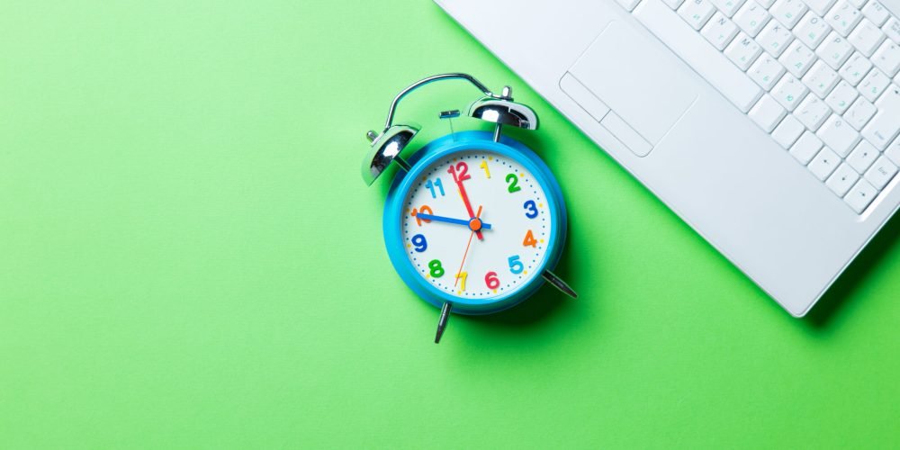 blue clock and laptop on the green background